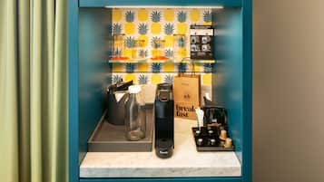 A kitchen counter with a coffee machine, a glass carafe, a bag of coffee beans, and a bag of bread.