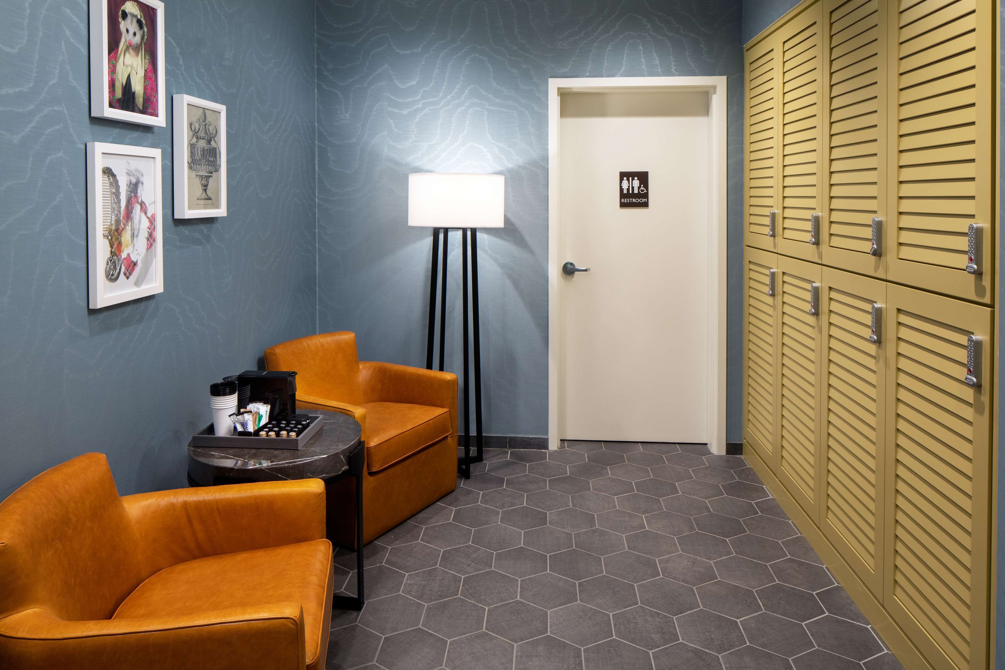 Habitación de hotel con pared azul, puerta blanca y zona de casilleros amarillos.