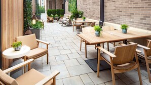 Een terras buiten met houten meubels en planten in potten.