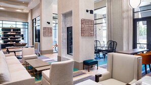 Een moderne hotel lobby met zithoeken, een receptiebalie en een boekenkast.