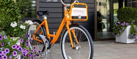 A bicycle with a delivery box labeled "canopy by Hilton" parked in front of a building.