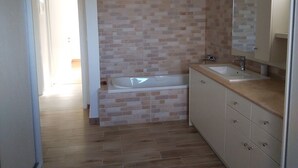 A bathroom with a bathtub, a sink, and a mirror. - La Maison Bleu (Messini)