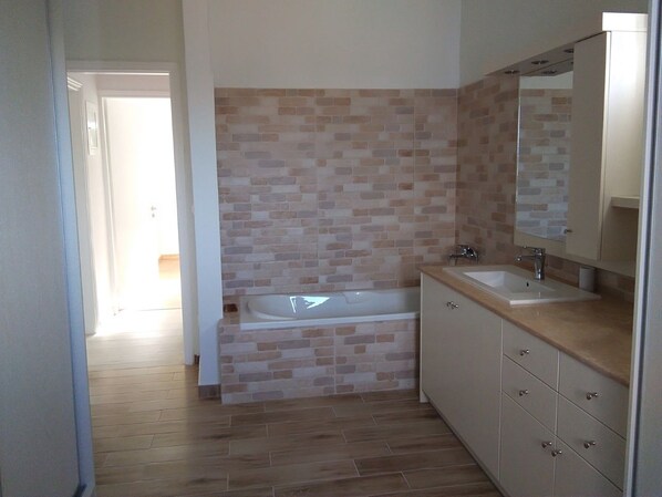 Un baño con bañera, lavamanos y espejo.
