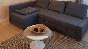 Uma sala de estar moderna com um sofá seccional, uma mesinha com um cesto e iluminação pendente.