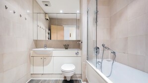 Une salle de bain moderne équipée de toilettes, d’un lavabo et d’une douche à parois de verre.