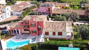 Un quartier résidentiel où les maisons se distinguent par leurs toits recouverts de tuiles rouges, une piscine et une vue sur la mer.