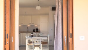 Une cuisine avec des meubles blancs, une table à manger avec des chaises et une machine à café.