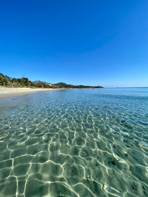 Ein heller Strand mit flachem Wasser, einem sandigen Ufer und einer entfernten Bergkette.