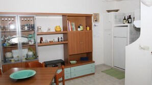 Une cuisine de taille réduite comprenant une table à manger, des placards en bois et un réfrigérateur.
