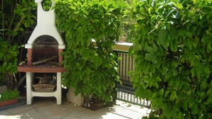 Un barbecue doté d’une cheminée blanche, entouré d’un feuillage verdoyant et luxuriant.