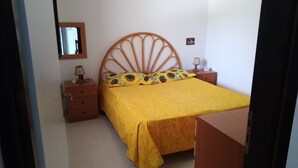 Une chambre à coucher comprenant un lit, une table de chevet, une commode, un miroir et une horloge murale.