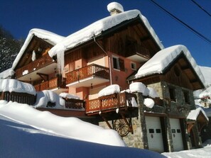 Traditional chalet-style building with a wooden balcony and stone facade.