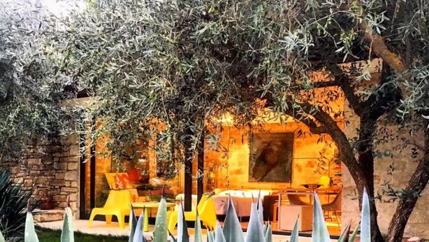 A patio area with a stone wall, yellow chairs, and a table. - ATELIER DEI CILIEGI (CAMMARATA)