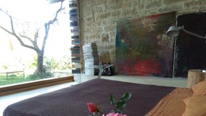 A bedroom with a large bed, a window with a view of trees, a bookshelf, and a painting on the wall. - ATELIER DEI CILIEGI (CAMMARATA)