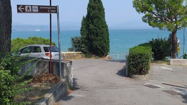 A parking area with a sign indicating a path to a lake.