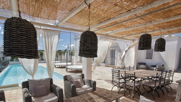 Ein Außenbereich mit Korbmöbeln, einem Pool und einer überdachten Terrasse.