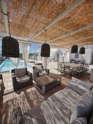 An outdoor lounge area with wicker furniture, a pool, and a covered patio.