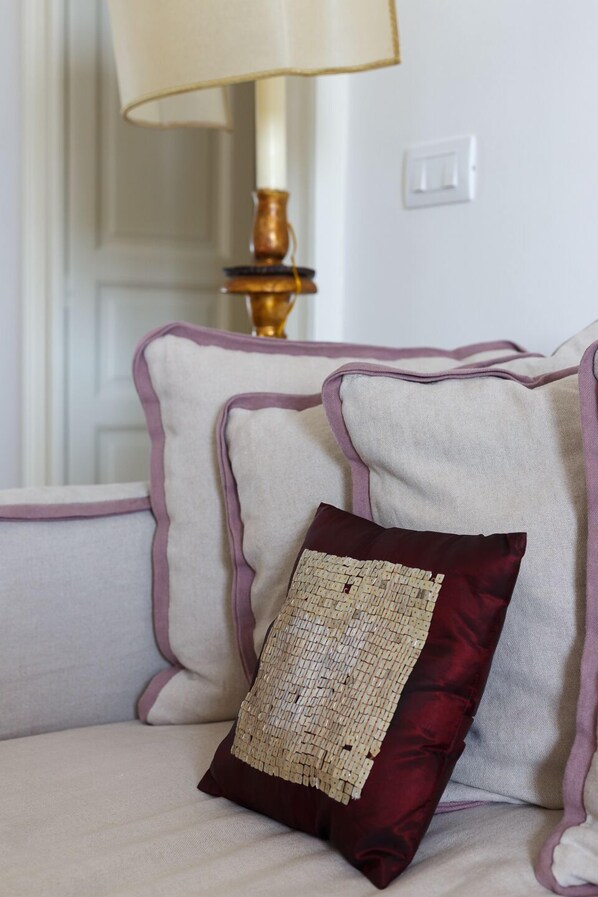 A sofa with a patterned cushion and a lamp in the background.