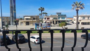 Ein Parkplatz mit Autos, ein hohes Gebäude mit einer Uhr und Palmen.