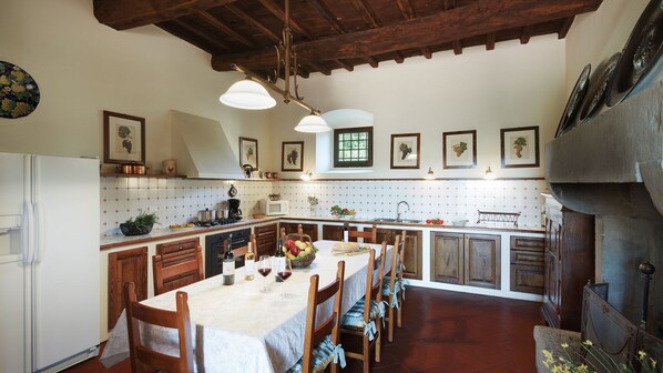 A kitchen with a central island, wooden cabinets, and a stone fireplace.