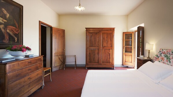 Une chambre à coucher avec un lit, une armoire en bois, une commode et un tableau accroché au mur.