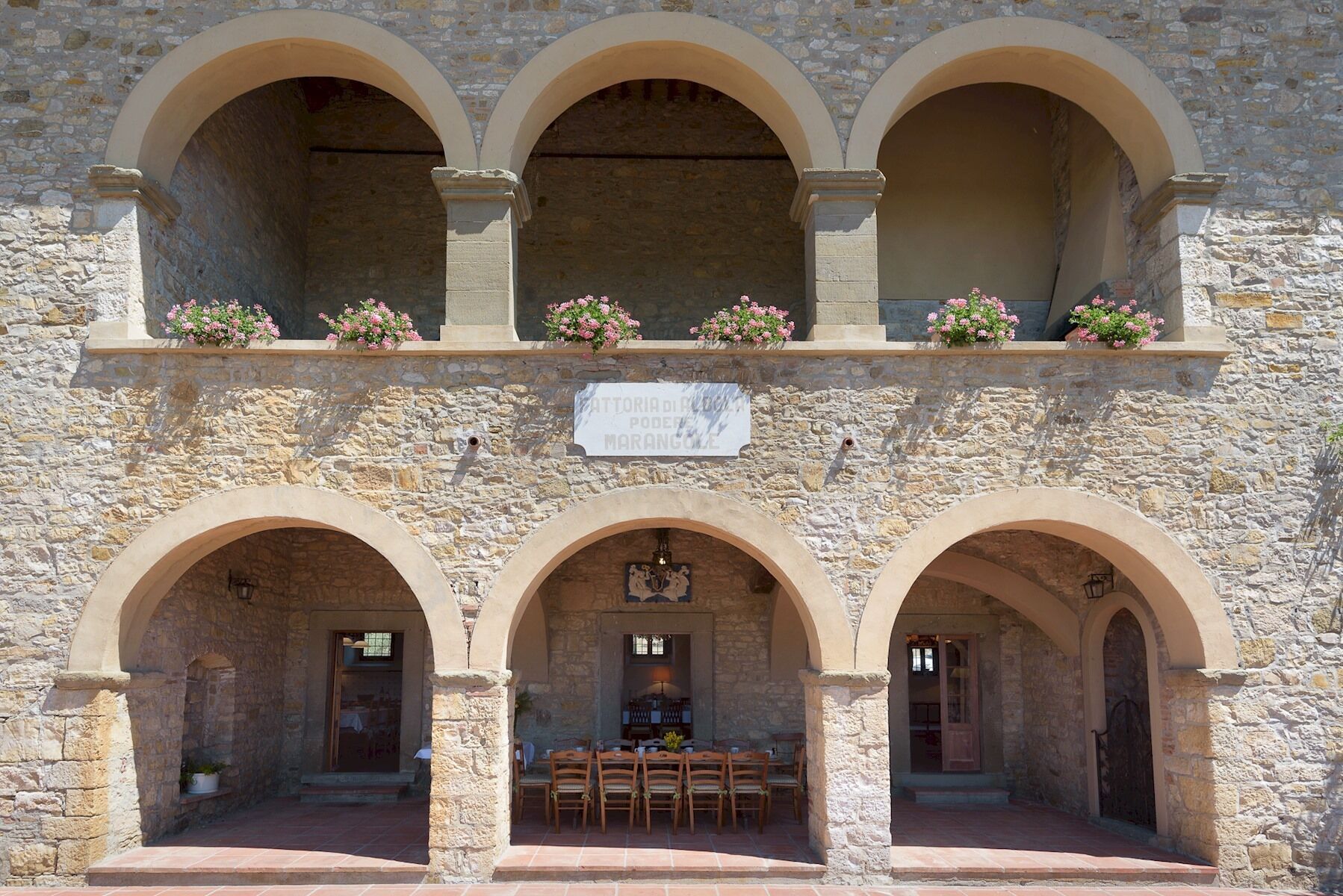 A stone building with three arches and a sign above them.