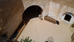Um pátio com um arco de pedra, um pequeno jardim e um espelho d'água.