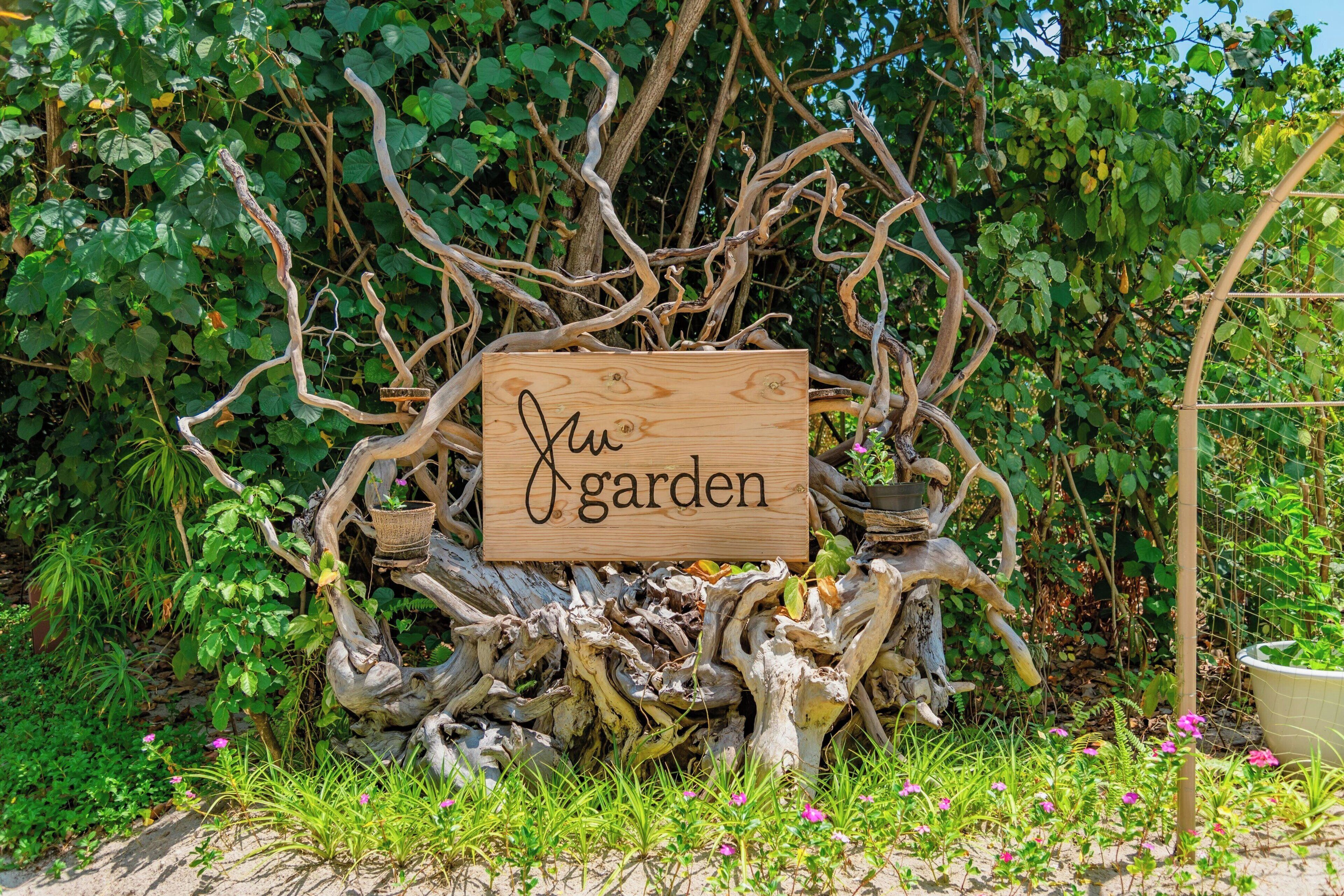 Une pancarte en bois portant l’inscription « Mon jardin », fixée sur le tronc d’un arbre décoratif.