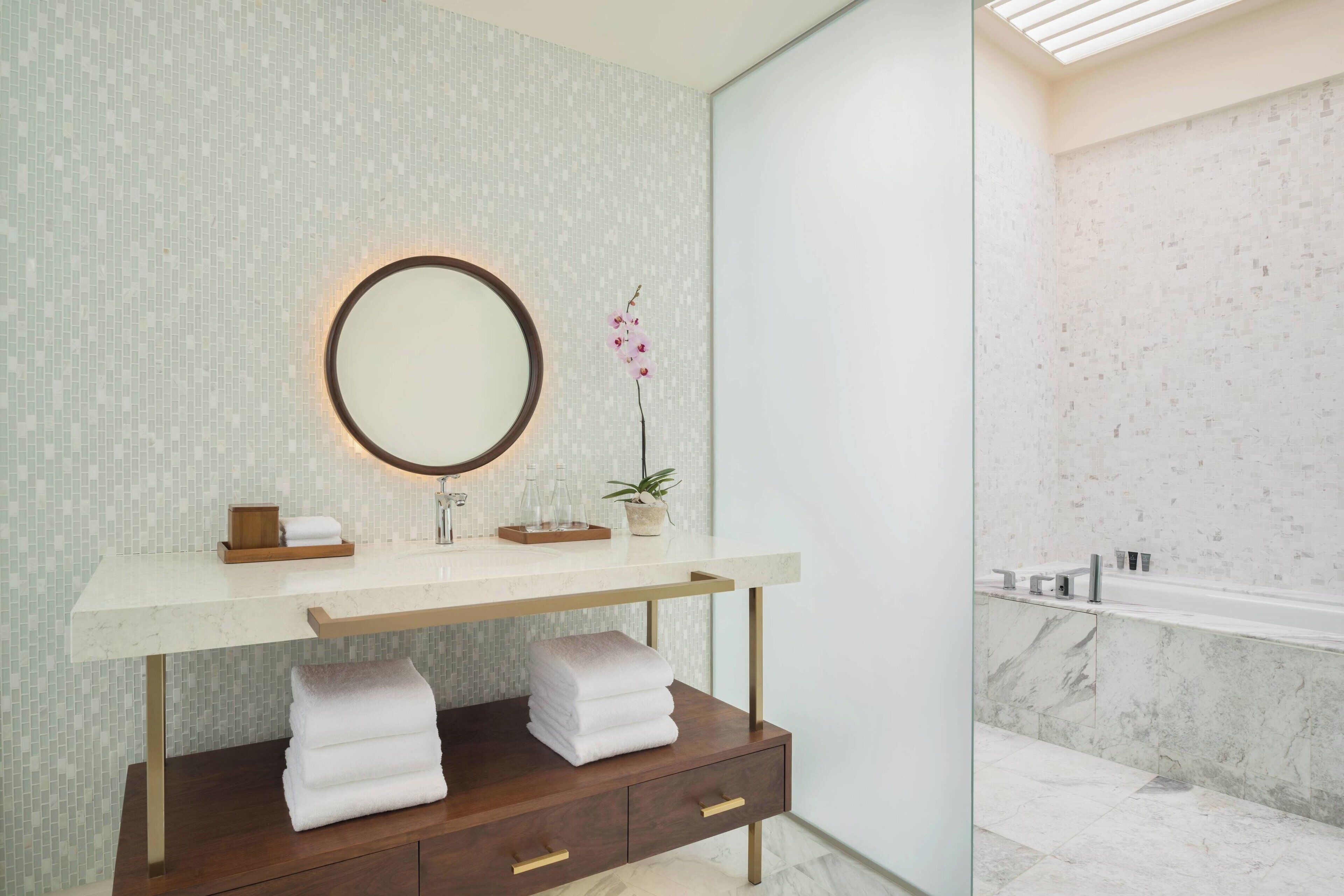 A modern bathroom with a marble sink, a wooden vanity, and a large mirror.