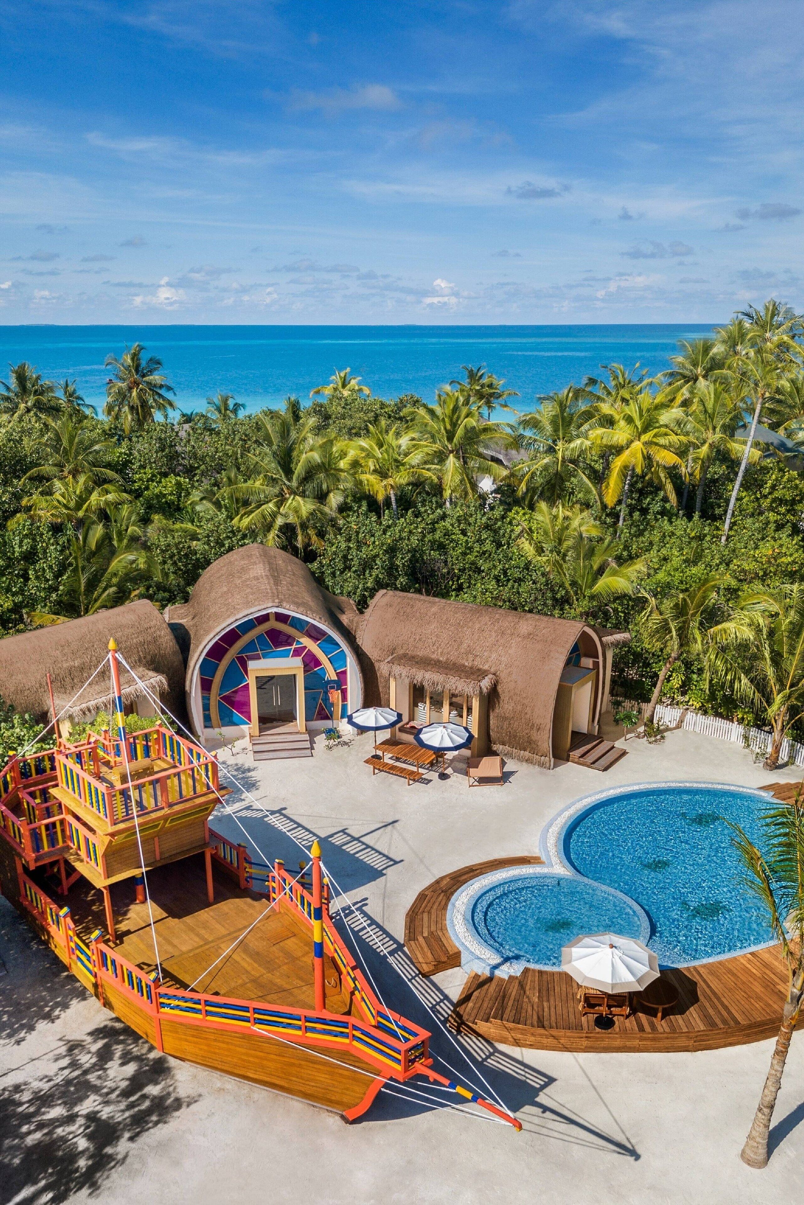 Un complexe hôtelier doté de bungalows aux toits de chaume, d’une terrasse en bois et d’une piscine.