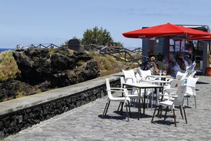Relax in a seaside seating area with ocean views, a wooden fence, and a small structure nearby.
