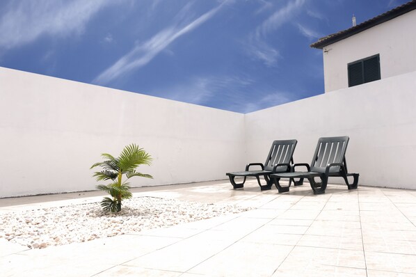 Relax in style on this outdoor patio with a palm tree and four comfortable lounge chairs.