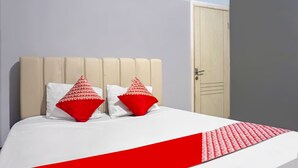A bed with a white and red bedspread, two pillows with red and white patterns, and a beige headboard. - Hotel O Puspita Guesthouse (Bekasi)