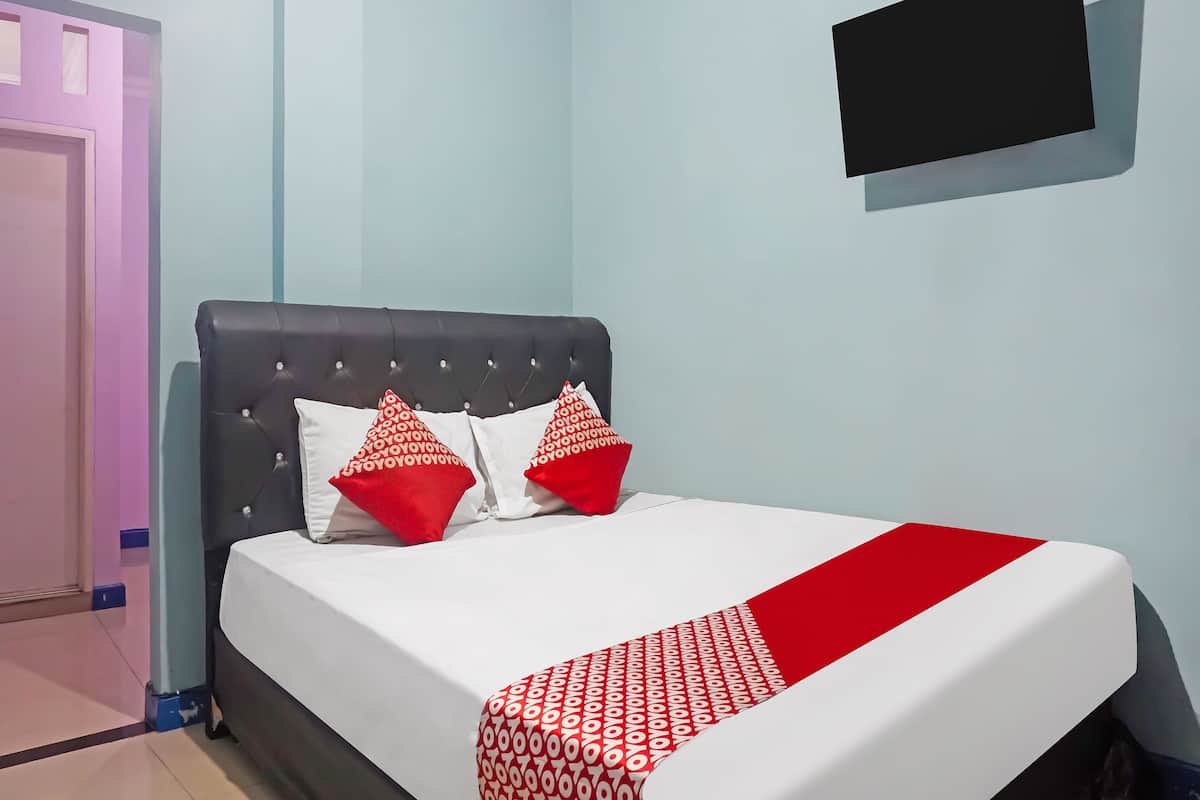 Ein Schlafzimmer mit einem Bett, einem an der Wand befestigten Fernseher und einer Tür.