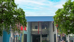 A two-story building with a flat roof and large windows. There are trees in front of the building, and a motorcycle parked outside. - Hotel O Puspita Guesthouse (Bekasi)