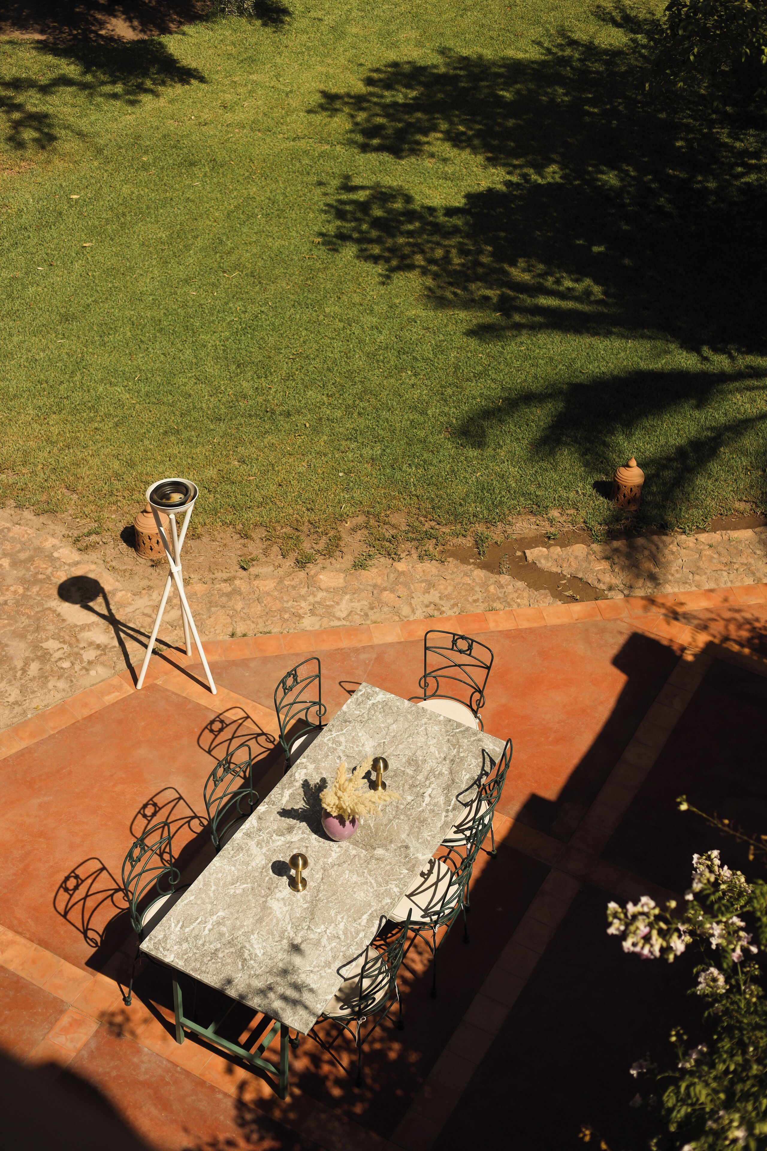 An outdoor patio with a table and chairs, a small stool, and a fire hydrant in the background.