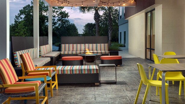 Un patio exterior con un sofá a rayas, sillas amarillas y una mesa.