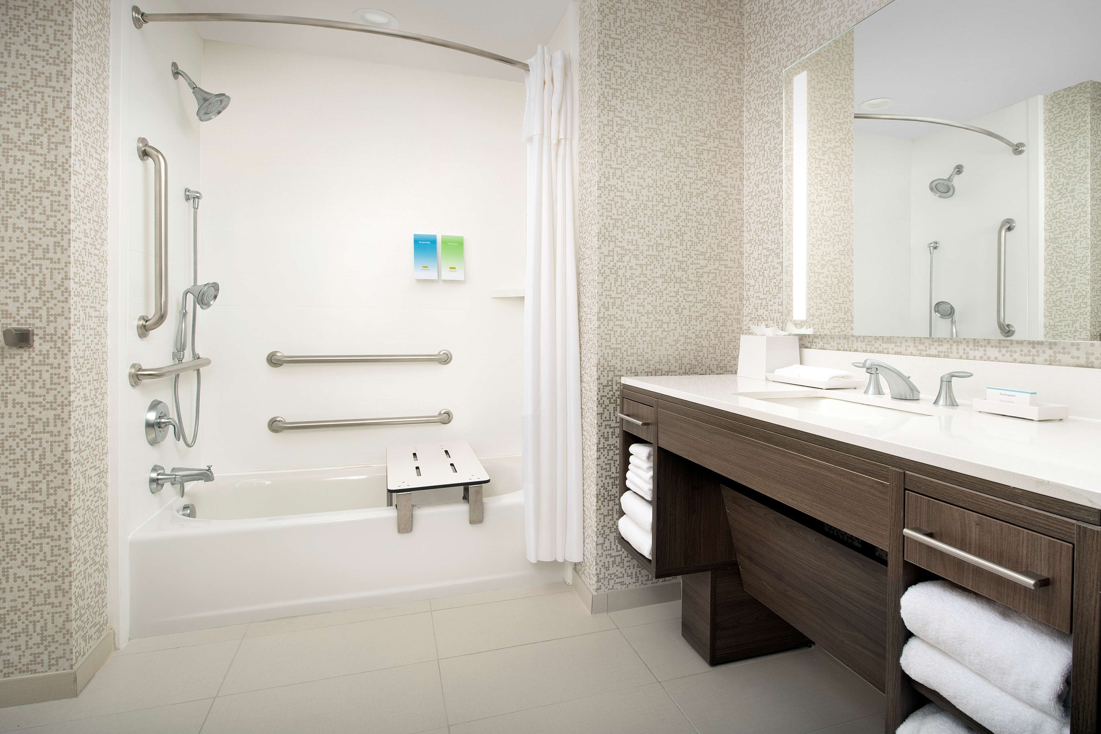 A modern bathroom with a bathtub, shower, and vanity.