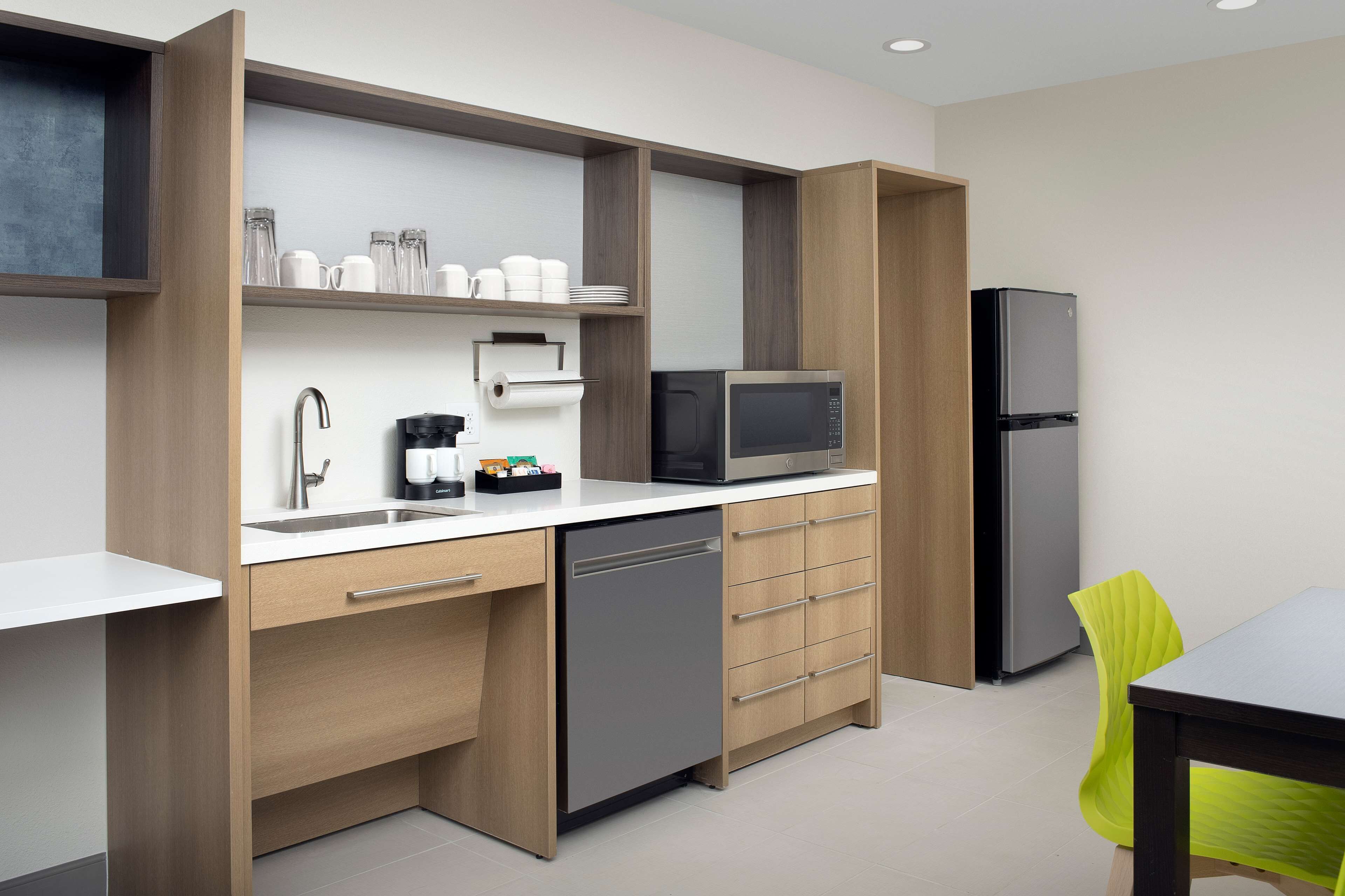 A modern kitchen with wooden cabinets, a dishwasher, a microwave, and a refrigerator.