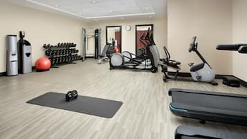 A gym with treadmills, elliptical machines, free weights, and exercise balls.