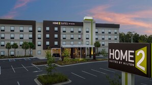 Un hotel con diseño moderno, que destaca por su entrada principal y un letrero que indica que es un Home 2 Suites by Hilton.