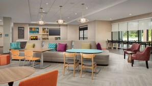 Un moderno vestíbulo de hotel con un sofá, sillas, una mesa y un televisor.