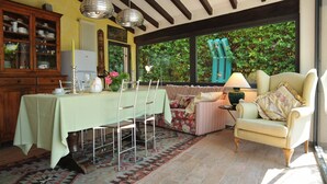 A cozy dining area with a table set for four, a floral sofa, and a chair with a lamp. - LAST MINUTE OFFER! Jacuzzi pool, Sauna, A / C, WiFi, close beaches & 5 Terre (ORTONOVO)