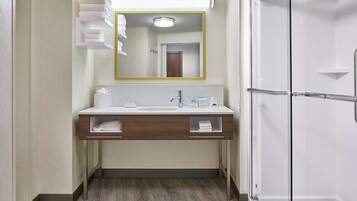 A bathroom with a white sink, a mirror, and a glass shower enclosure.