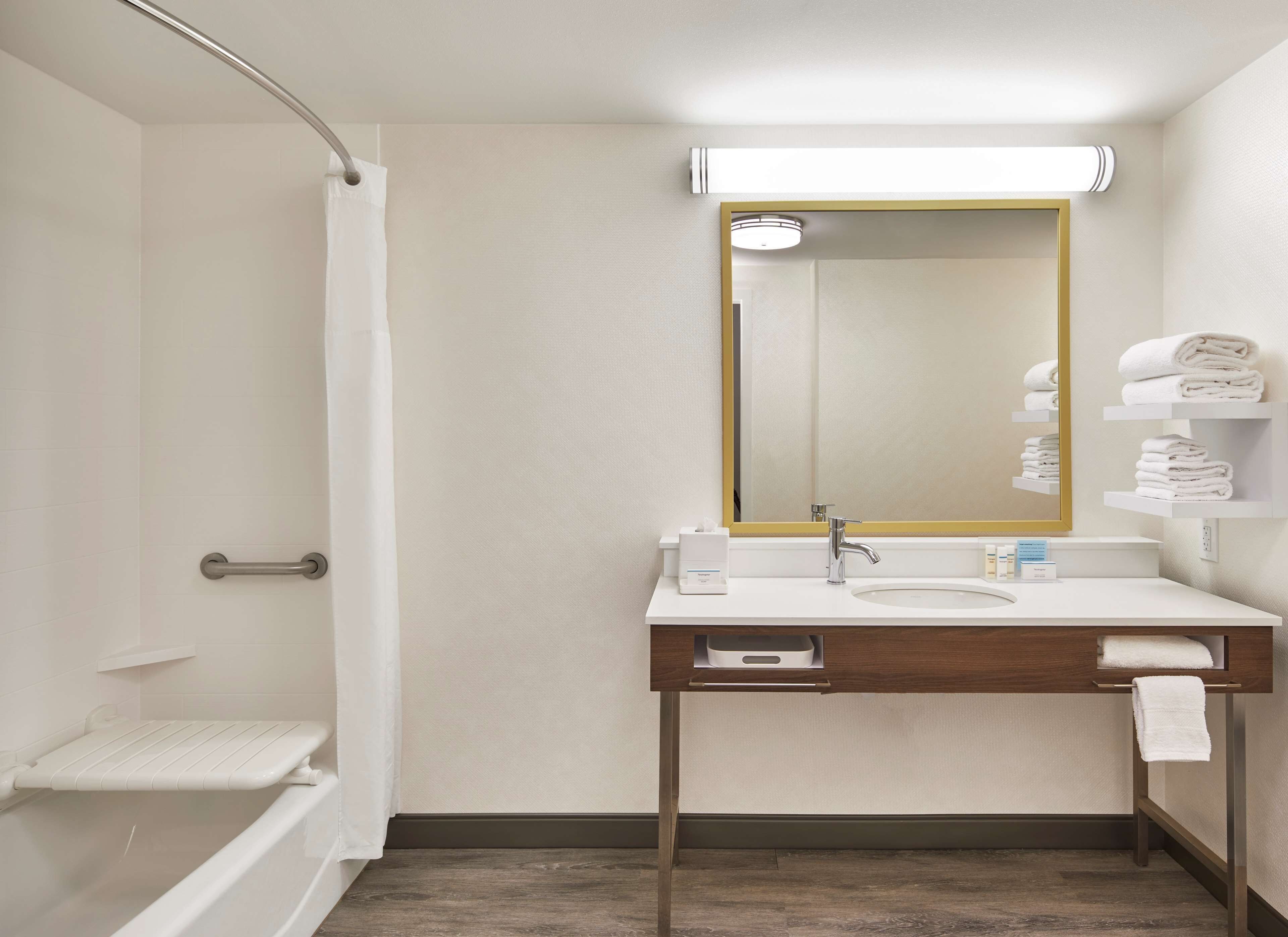 Un baño moderno con ducha, lavamanos, espejo y toallero.