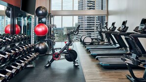 Een fitnessruimte met loopbanden, trainingsballen en gewichten.