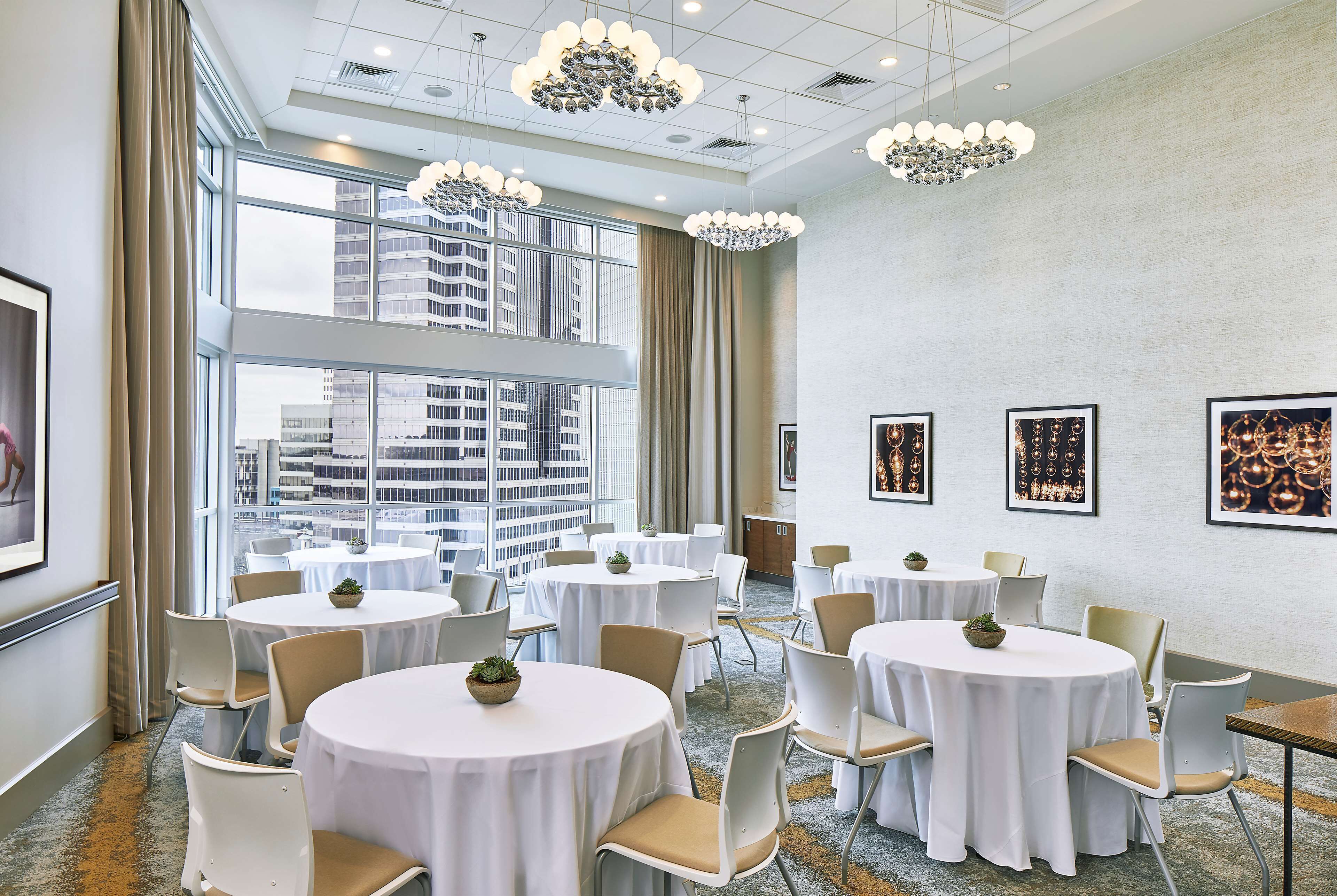 A conference room with round tables, chairs, and large windows offering a city view.