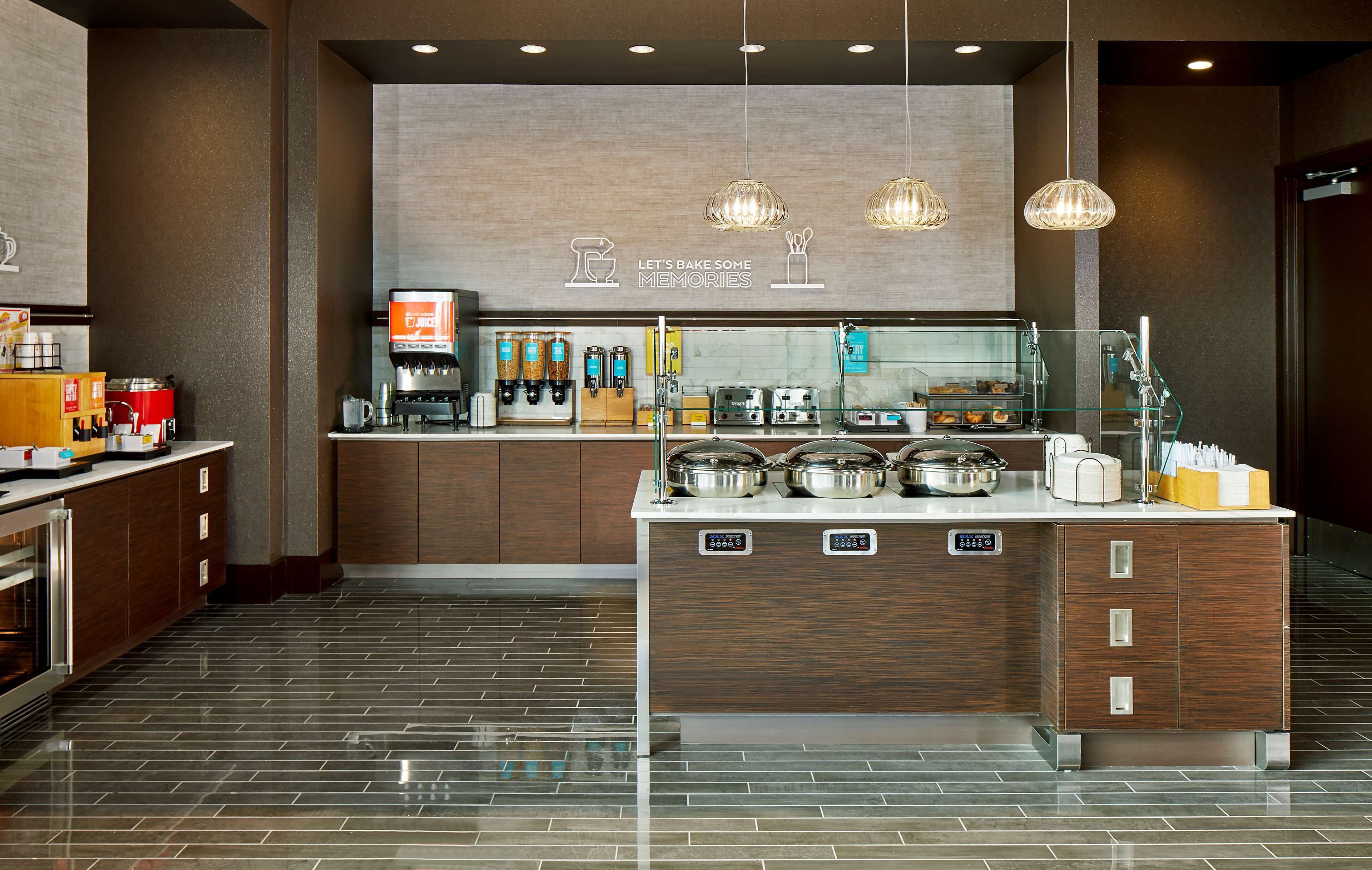 A modern kitchen with a central island, coffee machines, and a sign that reads "Let's bake some memories."