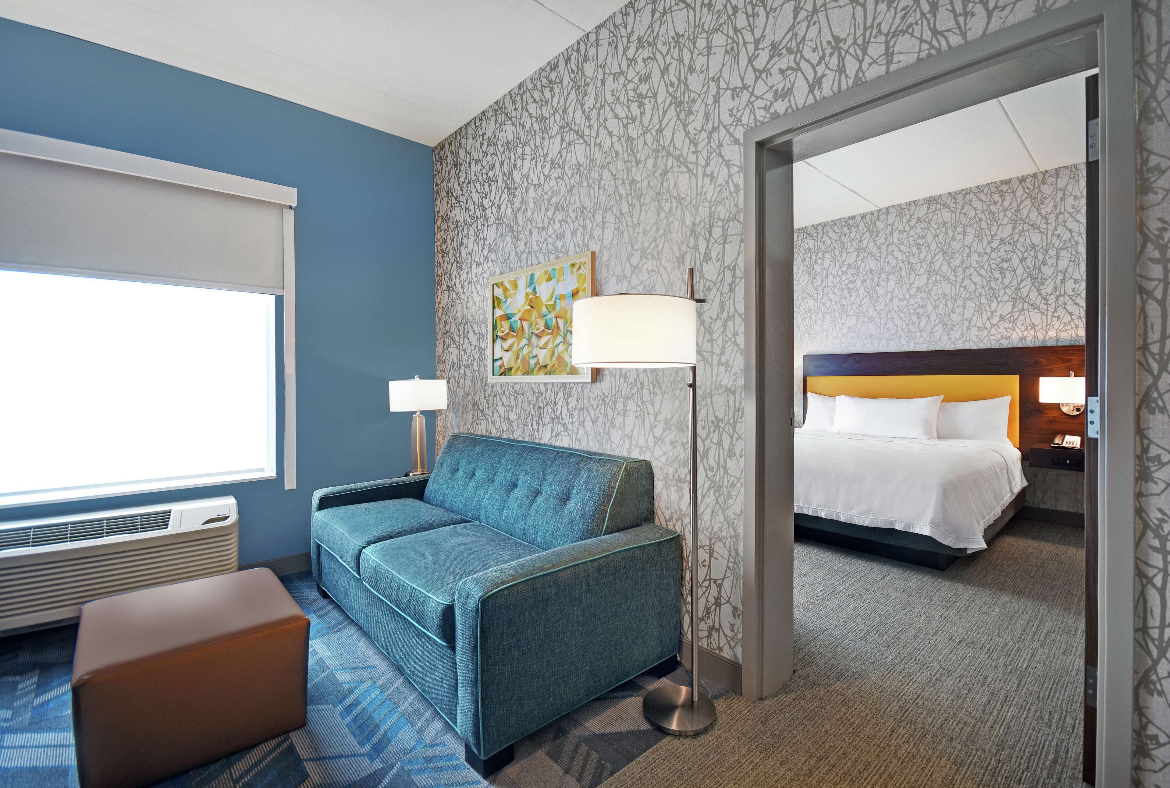 Ein Hotelzimmer mit Sofa, Bett, Lampe und einem Gemälde an der Wand.