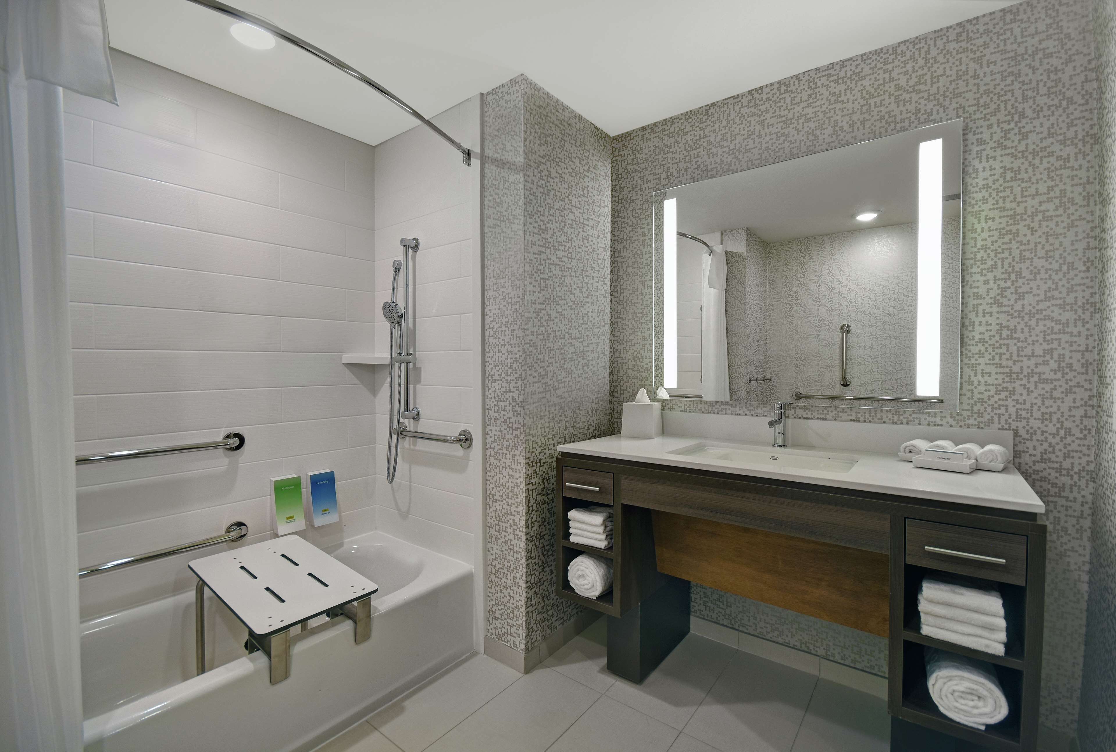 A modern bathroom with a bathtub, shower, and vanity with a mirror.